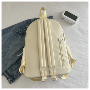 Detailed back view of cream backpack featuring padded shoulder straps and anti-theft zipper pocket
