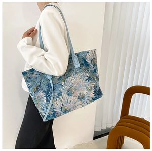 Detail of floral jacquard tote bag with blue leather handles and large interior capacity