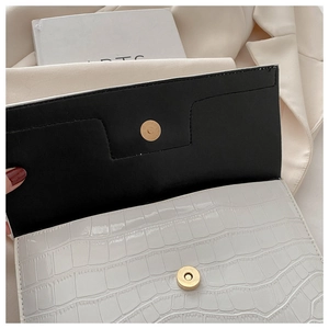 Detail of white crocodile embossed PU leather bag with golden magnetic snap closure