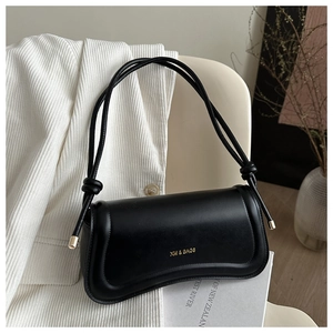 Close-up of black leather bag with gold logo and decorative contour stitching