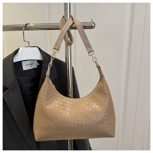 Elegant beige hobo bag with woven texture hanging on a garment rack next to a blazer