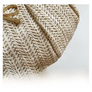 Close-up of beige woven straw texture with a shiny gold metal buckle detail