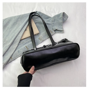 Detail view of black rectangular underarm bag with adjustable strap and metallic buckles