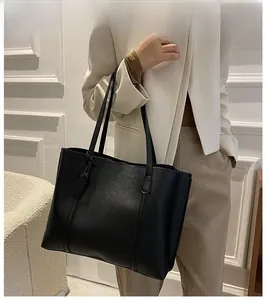 Lifestyle view of a large black soft leather tote bag worn by a model in casual style