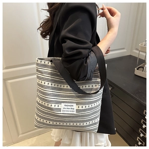 Détail du sac cabas en toile à rayures noires et blanches avec l'étiquette tissée