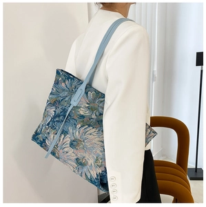 Close-up of vintage tote bag with blue floral jacquard pattern and leather straps