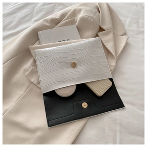 Detail of white crocodile embossed envelope clutch bag with metal magnetic closure