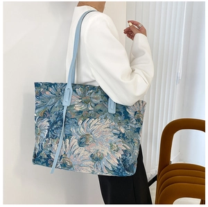 Detailed shot of large floral jacquard tote bag with blue leather straps on model