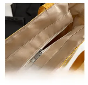 Detailed macro view of the smooth metal zipper and brown inner lining of the straw tote bag