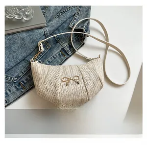 Detailed macro view of cream straw crescent bag with a gold bow buckle and denim jacket