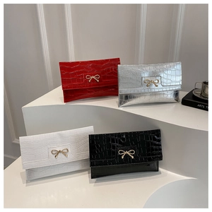 Detail of crocodile texture synthetic leather clutch bag with golden metal bow buckle