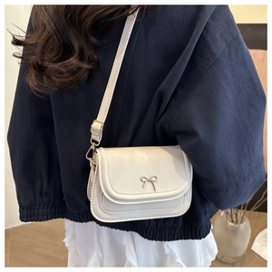 Détail de profil d'un petit sac à bandoulière blanc avec un nœud argenté décoratif chic.