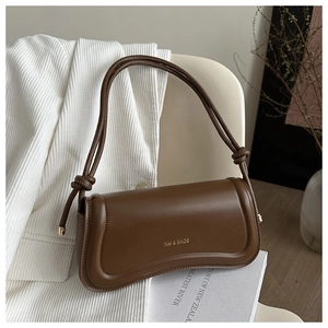 Detail of caramel curved shoulder bag with gold XM & BAGS logo and knotted strap