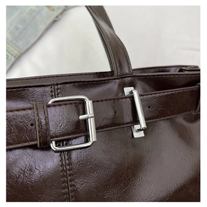 Detail of glossy deep reddish-brown leather texture and silver buckle on shoulder bag