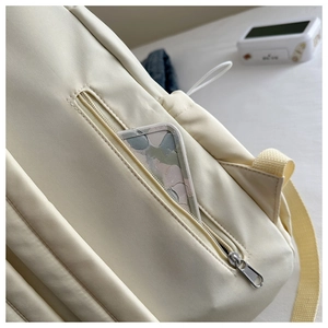 Détail macro du sac à dos matelassé blanc crème avec poche latérale zippée pour téléphone