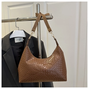 Large brown woven shoulder tote bag with textured pattern hanging on a garment rack