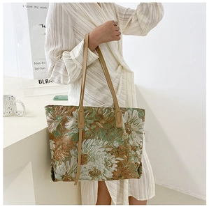 Detail of vintage floral tapestry tote bag featuring green woven patterns and leather handles