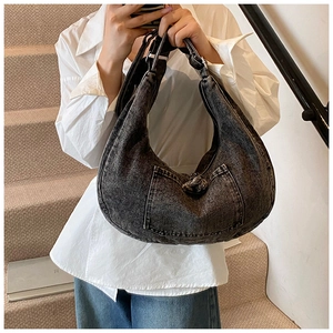 Detail of grey denim hobo bag featuring silver twist-lock buckle and washed texture