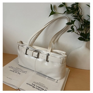 Detail of cream underarm bag showing glossy faux leather finish and silver buckle
