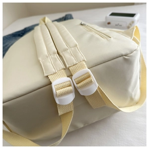 Détail des bretelles rembourrées et de la poche zippée cachée au dos du sac à dos crème