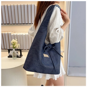 Detail of blue denim tote bag featuring drawstring bow decoration and FASHION & BAG label