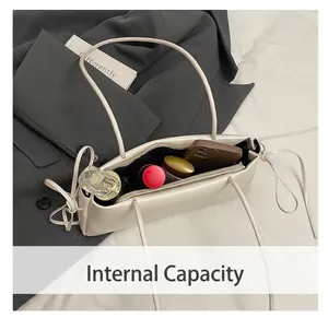 Internal view of cream minimalist shoulder bag showing storage for phone and cosmetics
