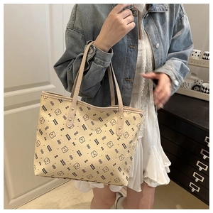 Detailed view of beige tote bag with black bear print and gold rivet handles on model