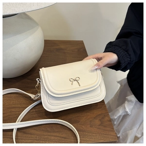 Vue détaillée du sac à bandoulière crème avec décoration noeud en métal