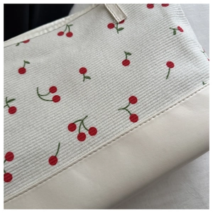 Detailed view of cherry print canvas tote bag with reinforced PU leather bottom stitching
