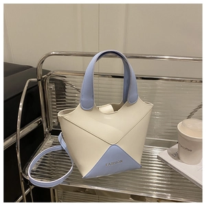 Détail d'un sac seau moderne en PU crème et bleu avec un design patchwork triangulaire