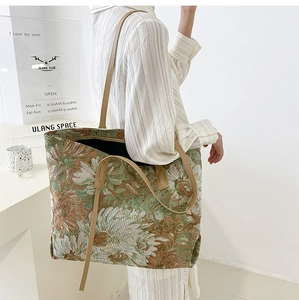 Close-up of vintage floral jacquard fabric and slim brown leather straps on a tote bag