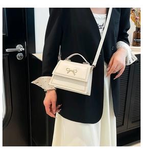 Elegante bolso bandolera blanco con lazo llevado por una modelo con chaqueta negra
