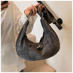 Detail of washed grey denim hobo bag with front pocket and decorative knot strap
