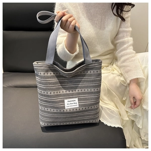Détail du sac cabas rayé avec poignées en nylon gris et texture tissée de haute qualité