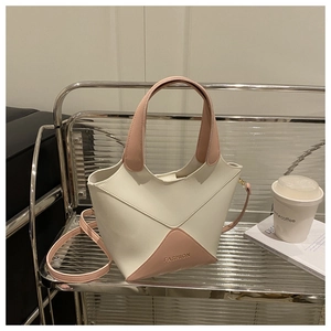 Détails d'un sac seau élégant en PU bicolore rose et crème sur une étagère moderne.