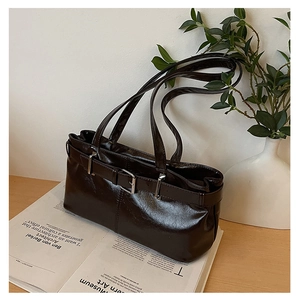 Detail of dark brown glossy leather underarm bag with silver buckle and sleek straps