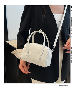 Detail of white lychee leather texture and embossed logo on crossbody bag with scarf