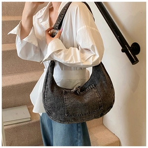 Close-up of dark grey washed denim crescent bag with a decorative front patch pocket