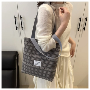 Détail du sac cabas en toile à rayures grises montrant l'étiquette de mode