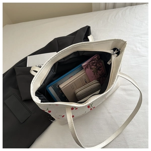 Detailed view of cherry print tote bag interior holding tablet, wallet and books