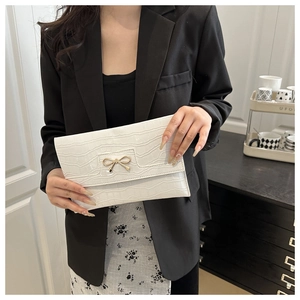 Detail of white stone texture PU leather clutch featuring a gold metal bow ornament