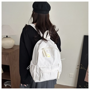 Vue arrière d'un sac à dos en toile blanche avec patch smiley jaune sur modèle décontracté