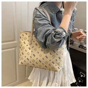 Close-up of cream leather tote bag with cartoon bear prints and fine pebble texture