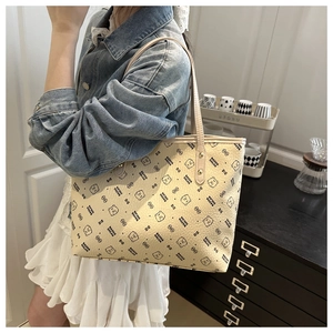 Side view of cream tote bag with bear print being worn by a model in casual setting