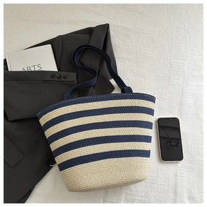 Detailed texture of blue and white striped straw tote bag with fabric handle on soft fabric