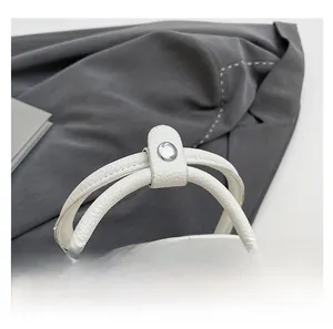 Détail d'un sac à main blanc en cuir grainé avec double fermeture éclair et poignée à bouton