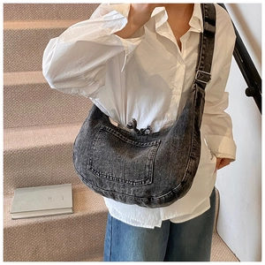 Detail of adjustable silver buckle and white stitching on a denim crescent tote bag