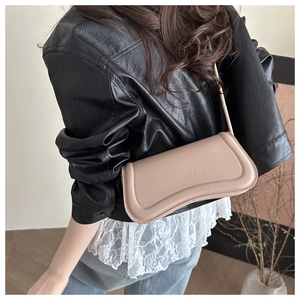 Close-up of nude beige faux leather shoulder bag with gold logo on a female model