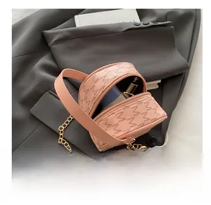 Pink round leather handbag featuring monogram M pattern and golden chain strap detail