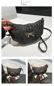 Detail of black woven crossbody bag featuring a golden metal bow and adjustable strap